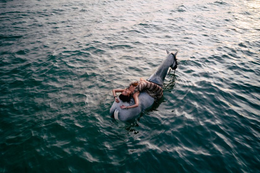 Girl riding horse in ocean